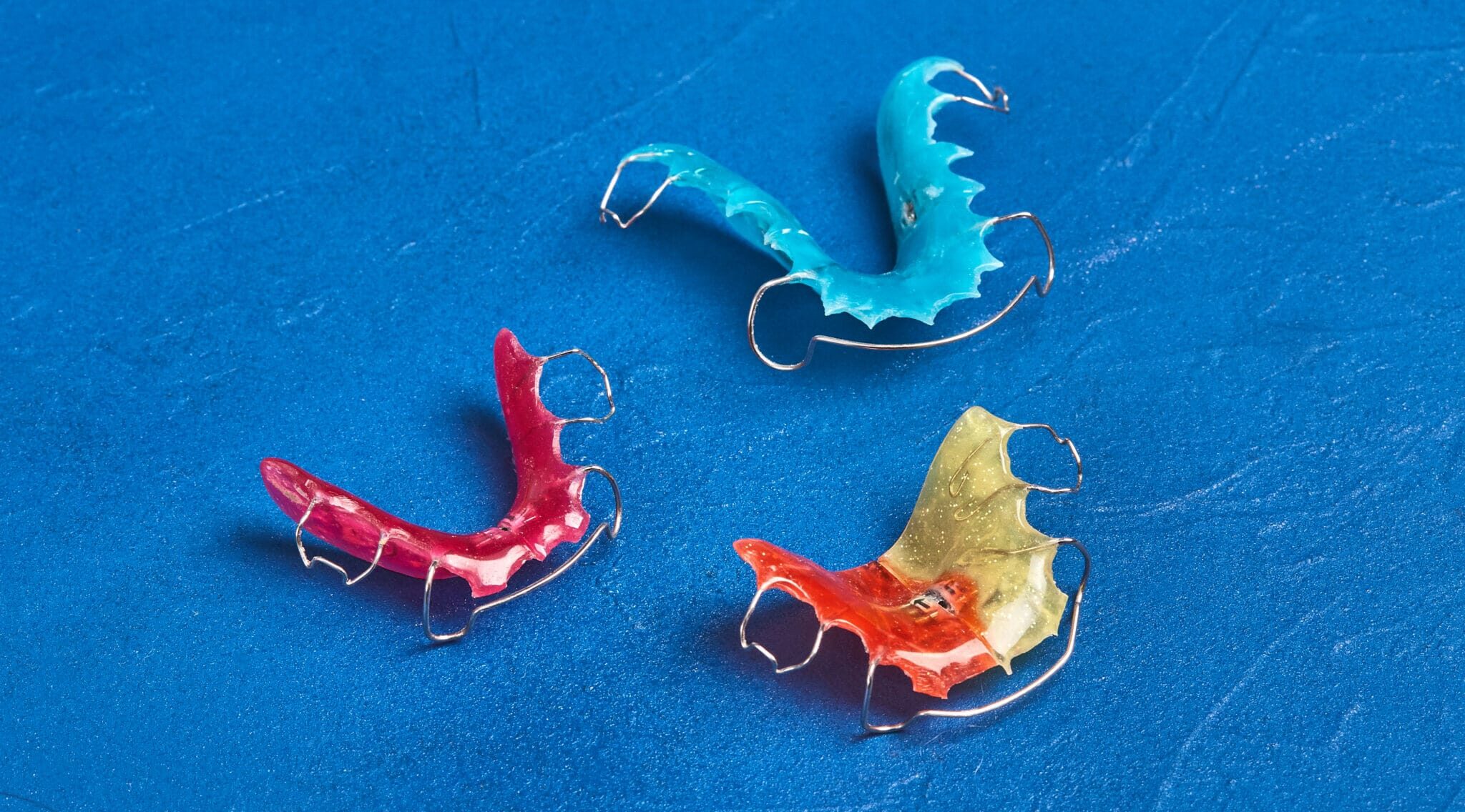 colorful dental braces or retainers for teeth on blue background