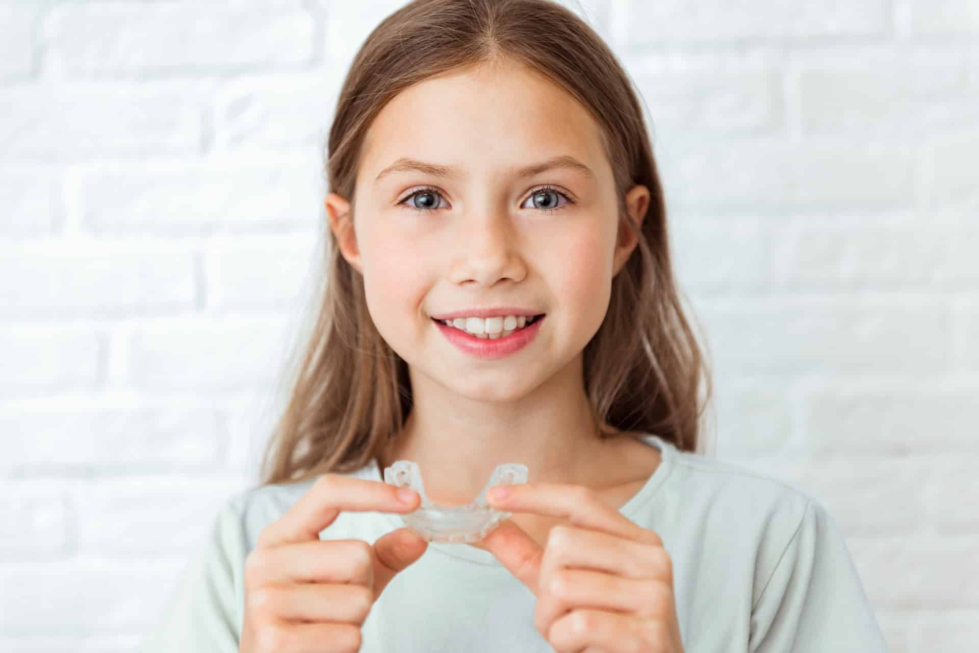 smiling child girl with perfect and healthy teeth using removable braces or aligner for straightening and whitening teeth. orthodontic treatment for correction of bite