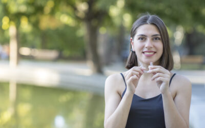 beautiful smiling woman is holding an invisalign brace