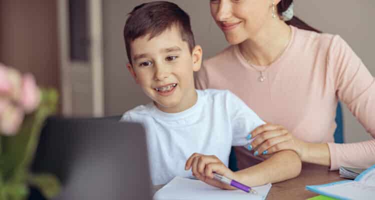 teen cute boy with braces learning homework at laptop computer and mom helping.